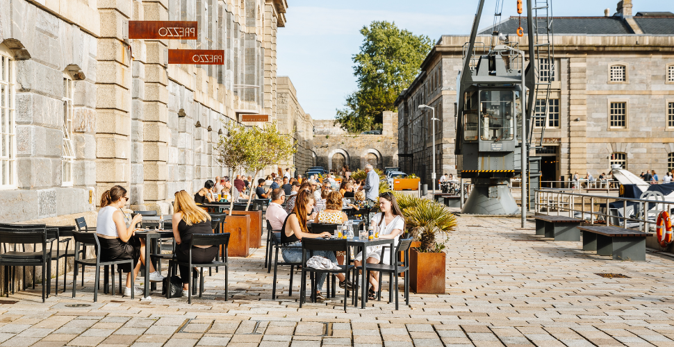 People sitting outside on the cobbles at the Royal William Yard